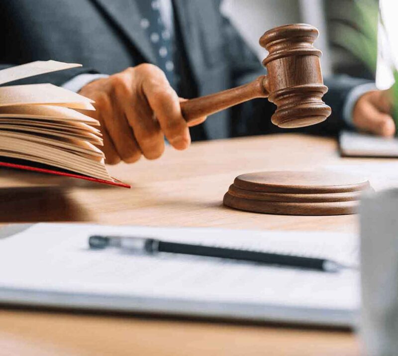 A person holding a gavel in front of papers.