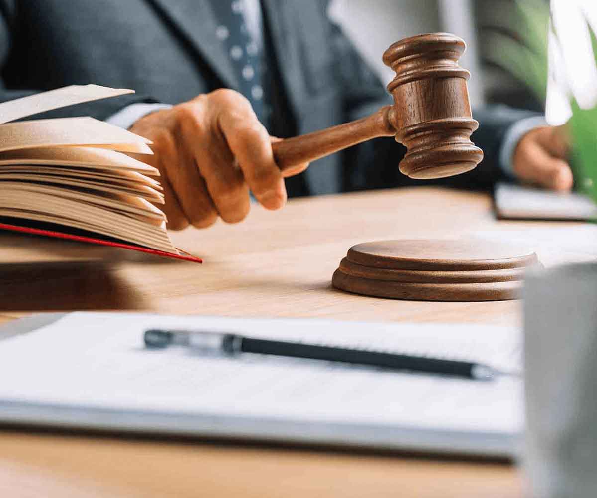 A person holding a gavel in front of papers.