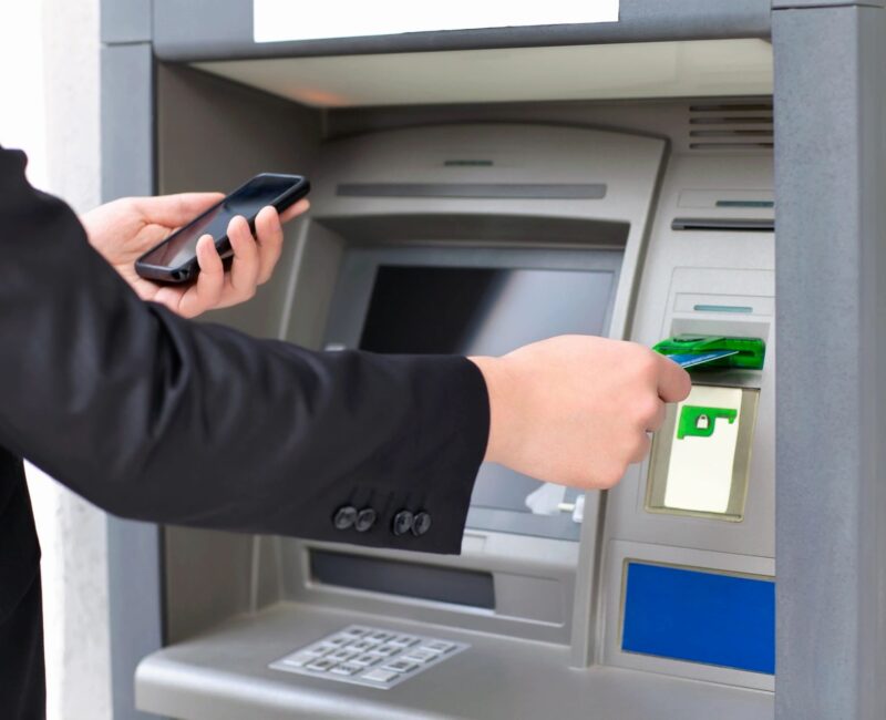 A person using their phone to withdraw money from an atm.