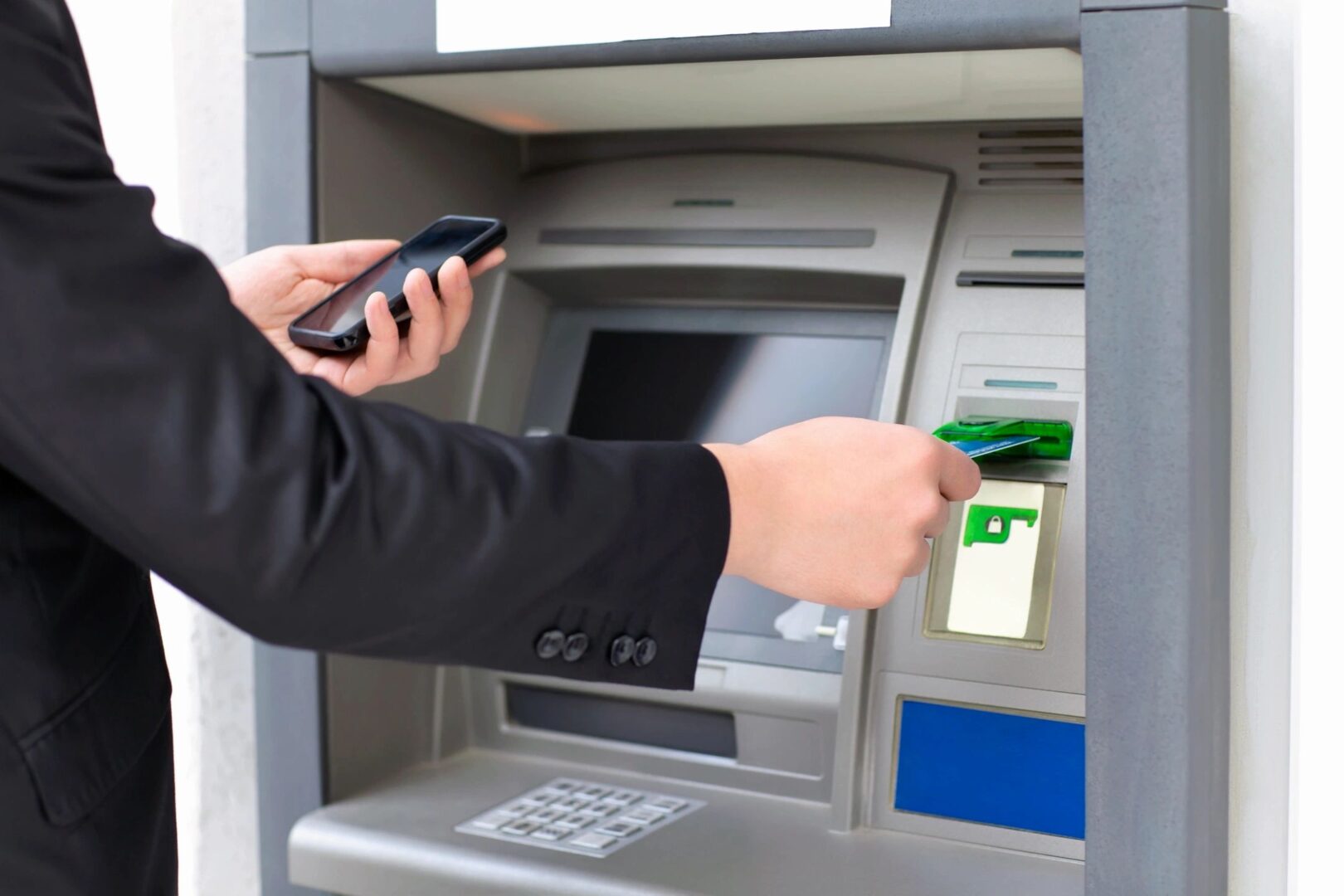 A person using their phone to withdraw money from an atm.